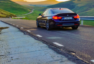 Black BMW driving on a valley road